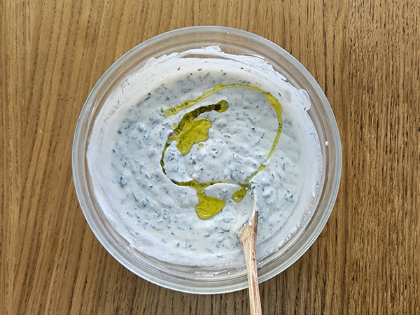 Filet d'huile d'olive dorée versé sur le fromage frais aux herbes.