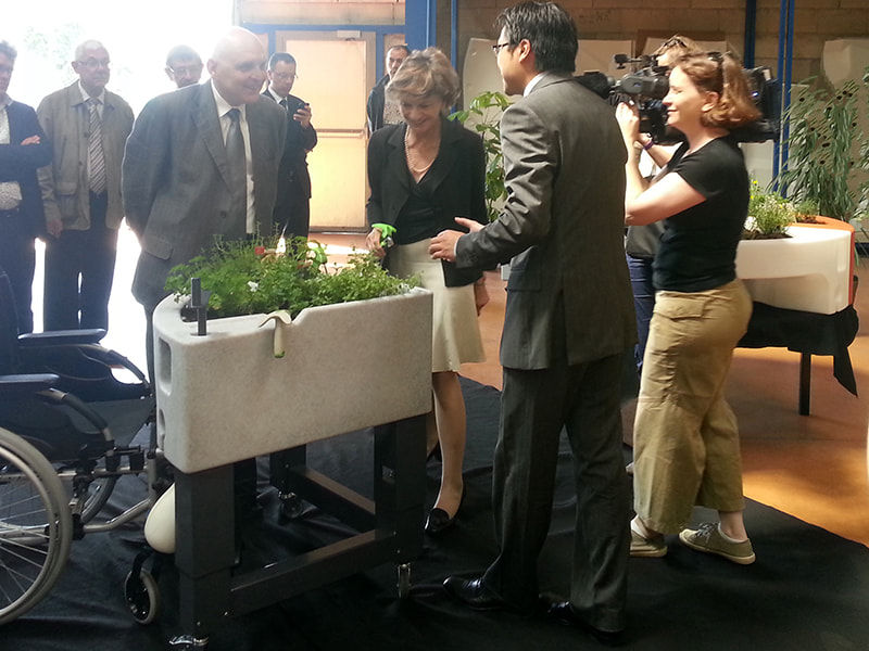 Mme Michèle Delaunay et le sénateur Claude Jeannerot observent une démonstration de jardinière ergonomique adaptée aux personnes à mobilité réduite.